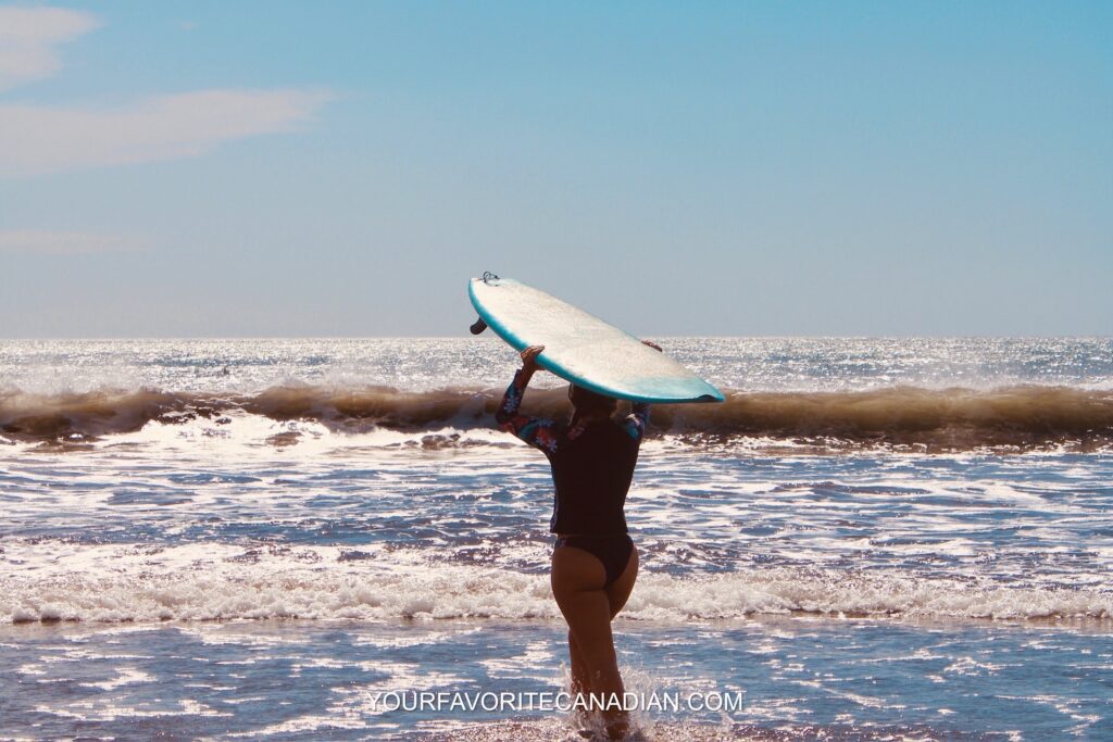 Woman standing with a surfboard on the beach