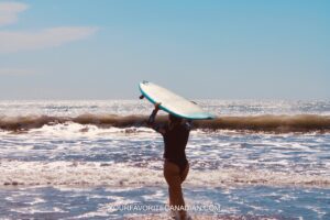 Woman standing with a surfboard on the beach